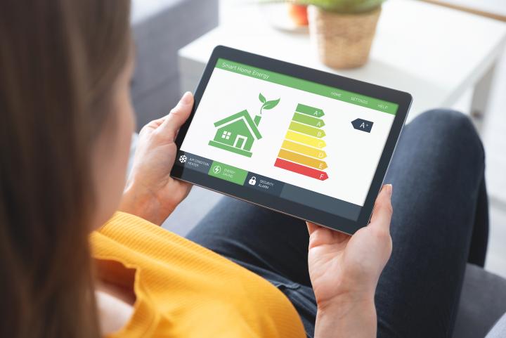woman sitting on a sofa holding a tablet device with a smart home energy app