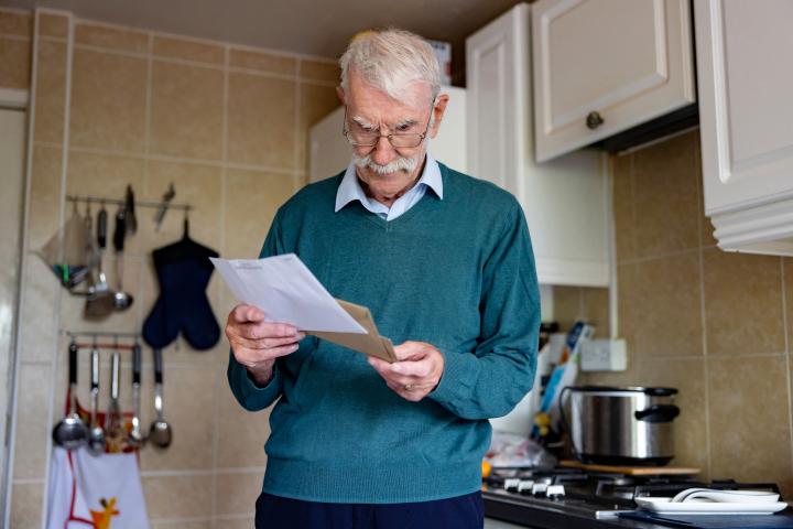 senior man at home reading an energy bill he got in his mail