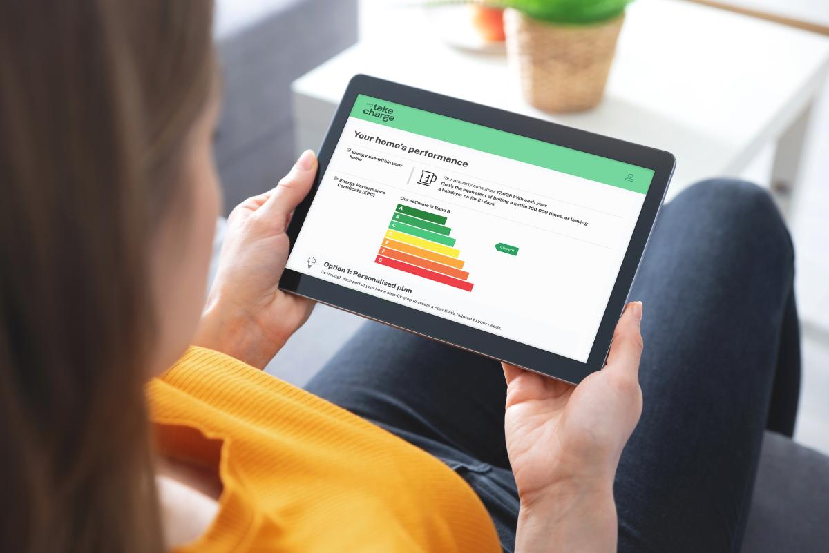woman sitting on a sofa holding a tablet device with a smart home energy app