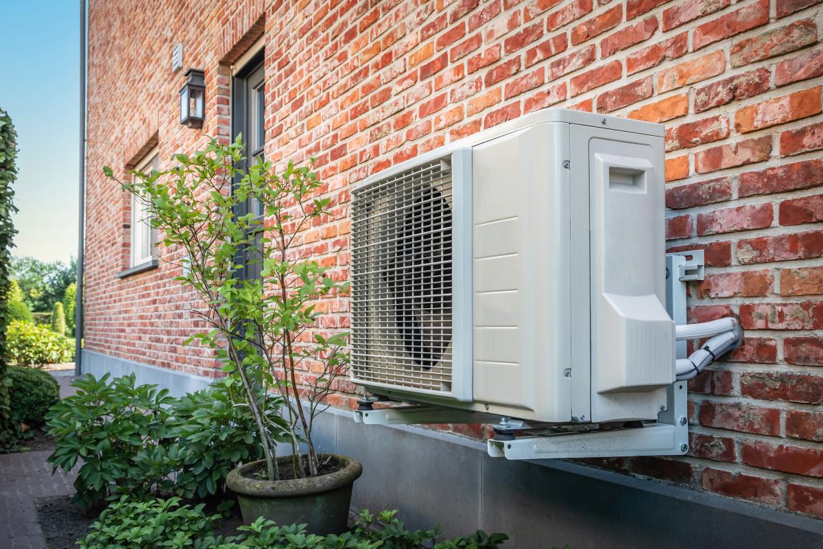 side view of an air to air heat pump hanging on brick wall of a house on a sunny day