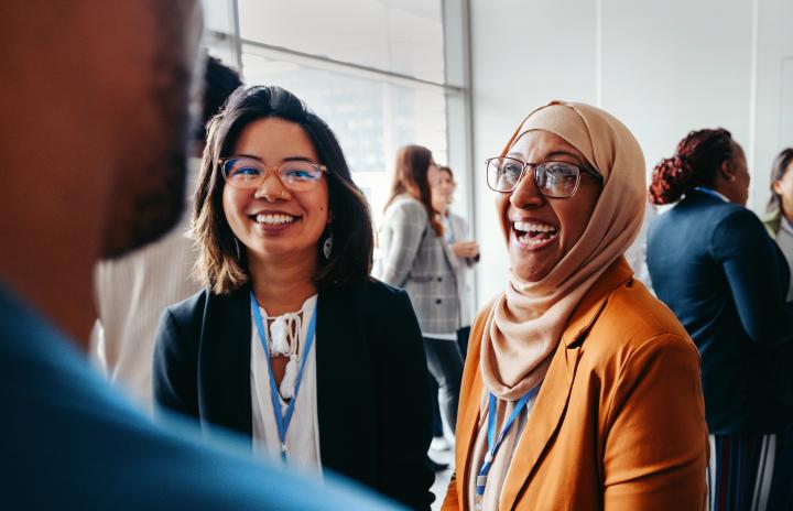 female colleagues interacting at a workshop, sharing happy smiles and engaging in lively conversations