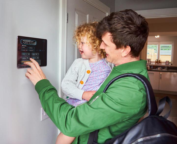 man holds his young daughter as he sets the smart home energy hub on the way out for the day