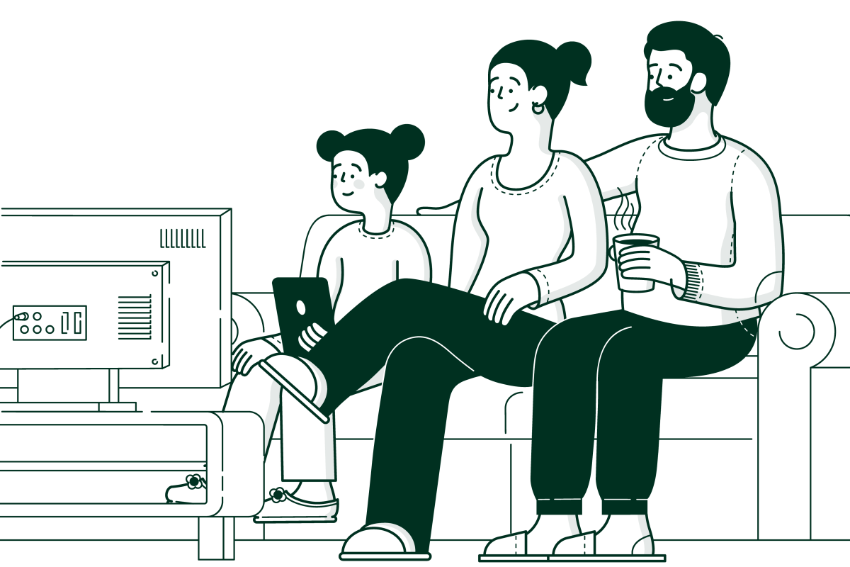 family sitting on a sofa watching TV with a cat padding past